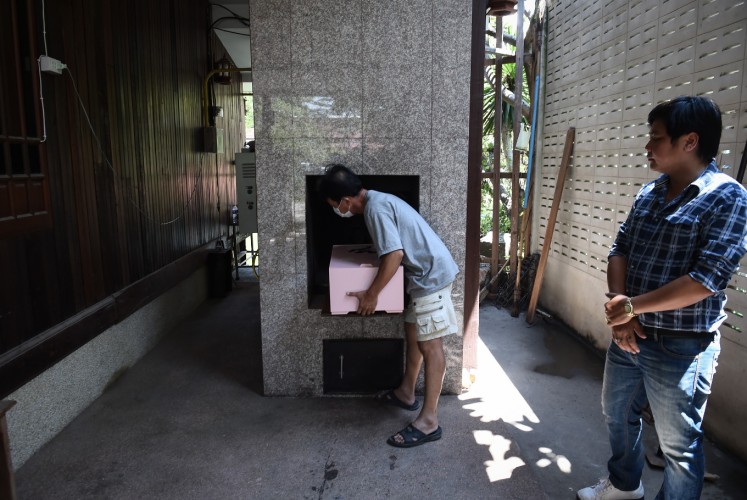 This photo taken on September 14, 2017 shows an undertaker placing the coffin of Dollar, a six-year-old Shih Tzu dog, inside the crematorium during the pet's funeral at Wat Krathum Suea Pla Buddhist temple in Bangkok. Pet cremations, complete with Buddhist rituals, are popping up across Bangkok for dogs, cats and even monkeys. In a devout Buddhist kingdom where religion and superstitious beliefs entwine, some pet owners believe the monk-led send off will boost their pets' chances of being reincarnated as a higher being.