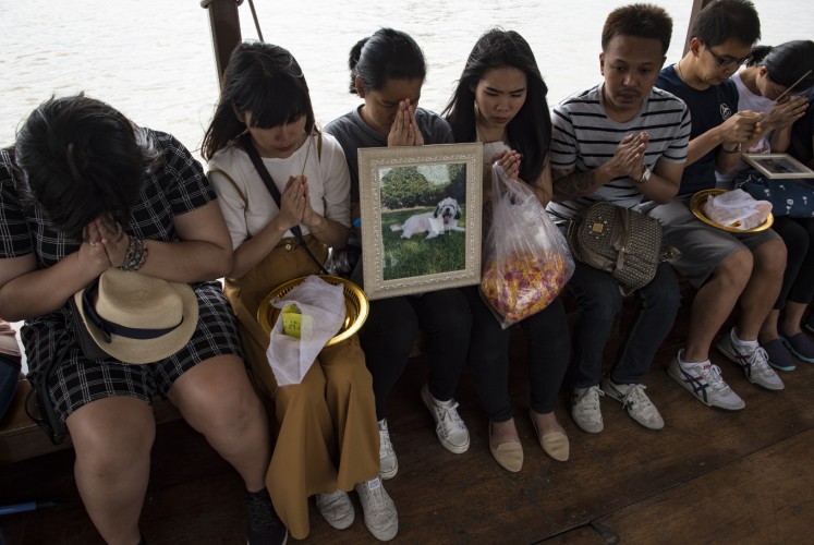 This photo taken on November 5, 2017 shows mourners praying for their pets before releasing their bones and ashes in the Chaopraya river in Bangkok. Pet cremations, complete with Buddhist rituals, are popping up across Bangkok for dogs, cats and even monkeys. In a devout Buddhist kingdom where religion and superstitious beliefs entwine, some pet owners believe the monk-led send off will boost their pets' chances of being reincarnated as a higher being.