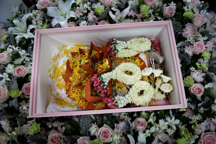 This photo taken on September 14, 2017 shows Dollar, a six-year-old Shih Tzu dog, inside a coffin with flower garlands and gold joss paper during the pet's funeral at Wat Krathum Suea Pla Buddhist temple in Bangkok. Pet cremations, complete with Buddhist rituals, are popping up across Bangkok for dogs, cats and even monkeys. In a devout Buddhist kingdom where religion and superstitious beliefs entwine, some pet owners believe the monk-led send off will boost their pets' chances of being reincarnated as a higher being.