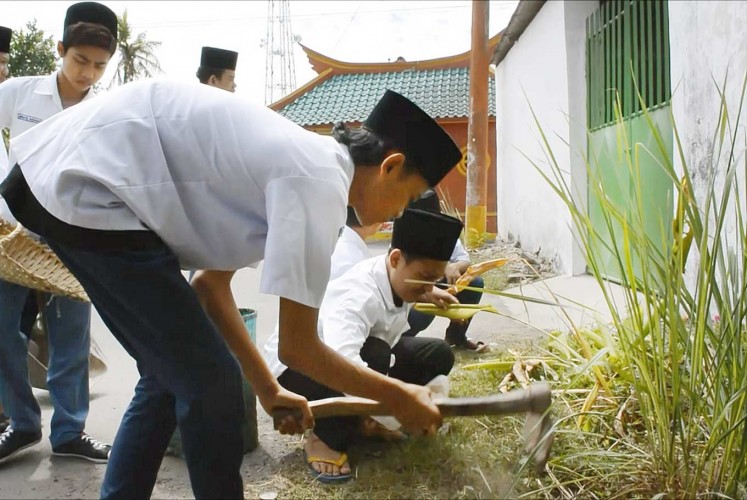 Helping the community: Kauman Islamic Boarding School students work together to clean up the surrounding neighborhood, which is predominantly ethnic Chinese.
