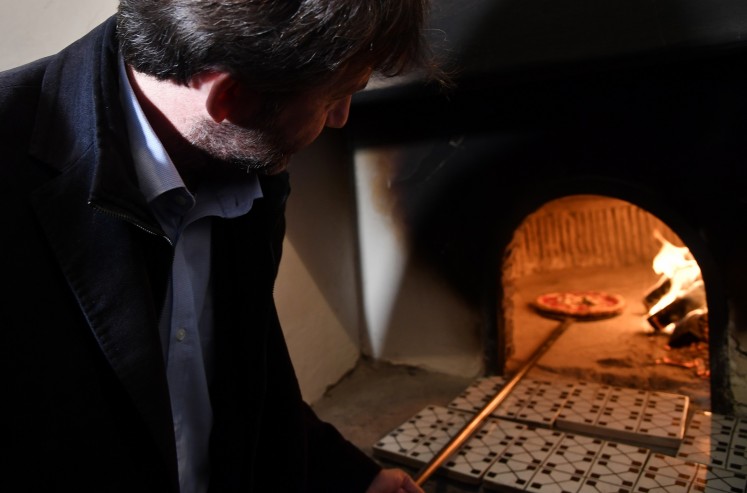 Italy's Culture Minister Dario Franceschini takes out a pizza from the first stone oven where was cooked a Pizza Margherita, on December 6, 2017 at the Capodimonte museum in Naples.  