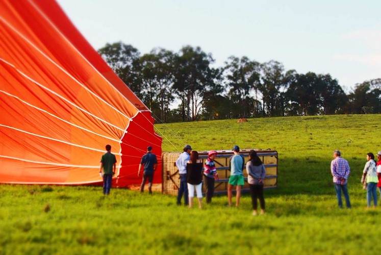 Down to earth: Passengers stand near a hot air balloon after riding in it for around 30 minutes. After the ride, the pilot and crew asked the passengers to help them roll up the balloon. 