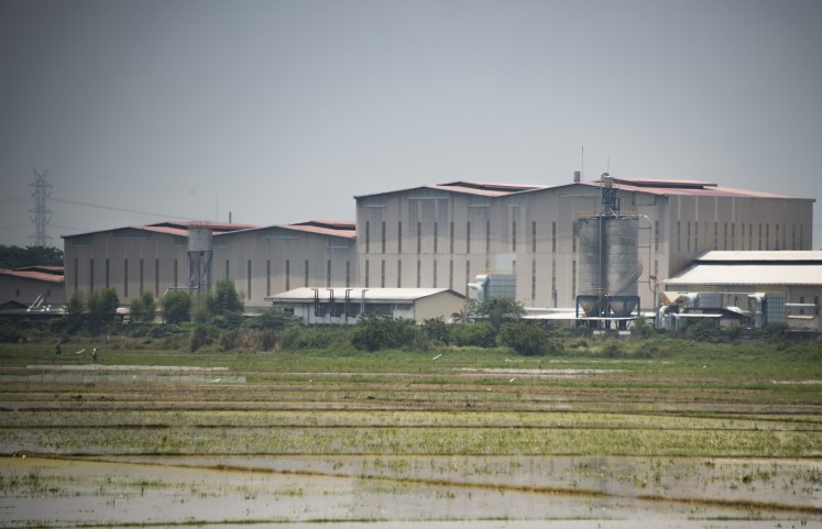 This photograph taken on October 24, 2017 shows paddy fields surrounding a factory which makes asbestos products in Cikarang, West Java province. 