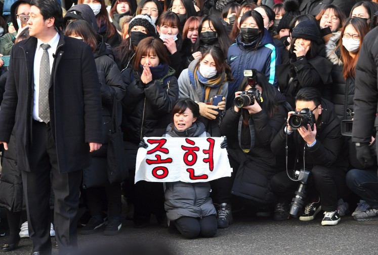 A fan of late SHINee singer Kim Jong-Hyun holds a banner reading 