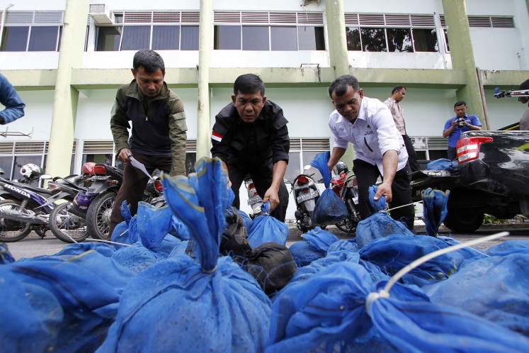 This file photo taken in Pekanbaru, Riau province on October 25, 2017 shows Indonesian officials unloading pangolins after a recent raid in Pekanbaru. Pangolin in Indnesia are at risk of extinction thanks to an illicit trade that sees thousands of the critically endangered trafficked each year, a stury showed on December 21, 2017.