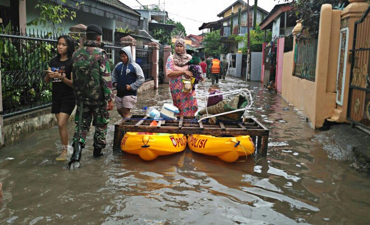 Evacuated: A military member evacuates a resident living on Jl.Swadaya, Makassar, South Sulawesi, to a temporary shelter.