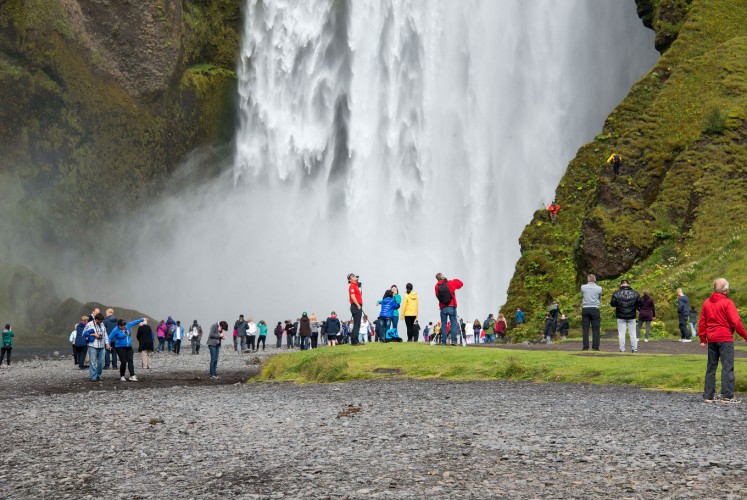Crowds form in front of the waterfall at Skogar, in Iceland.