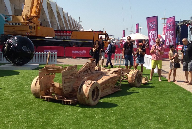 F1 fans observe Noor's 'Got Wood,' a wooden replica of an F1 racing car.