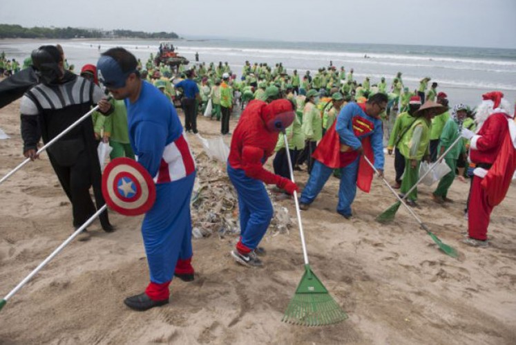 Cleaners dressed up in superhero costumes tidy up Kuta Beach, Bali. 