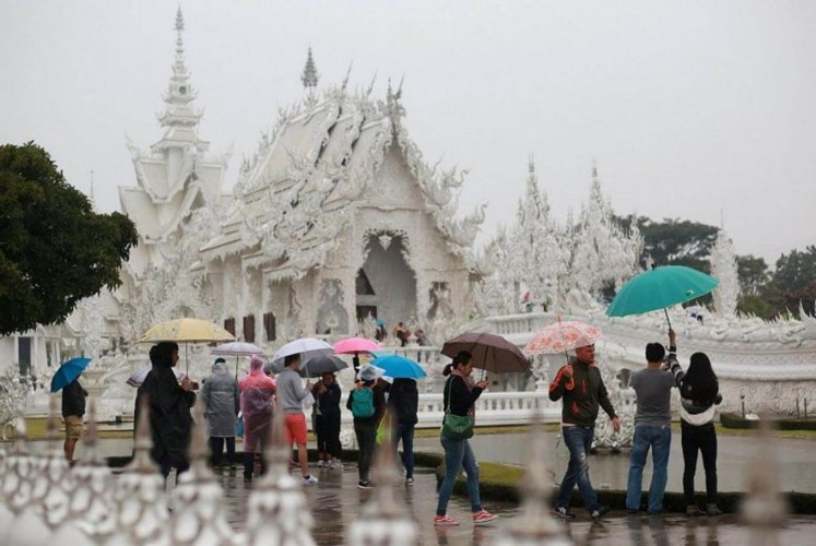 Tourists flock to Wat Rong Khun in Chiang Rai province despite the rain as a cold front from China and the weakening storm Tembin continued to influence weather patterns across Thailand. 