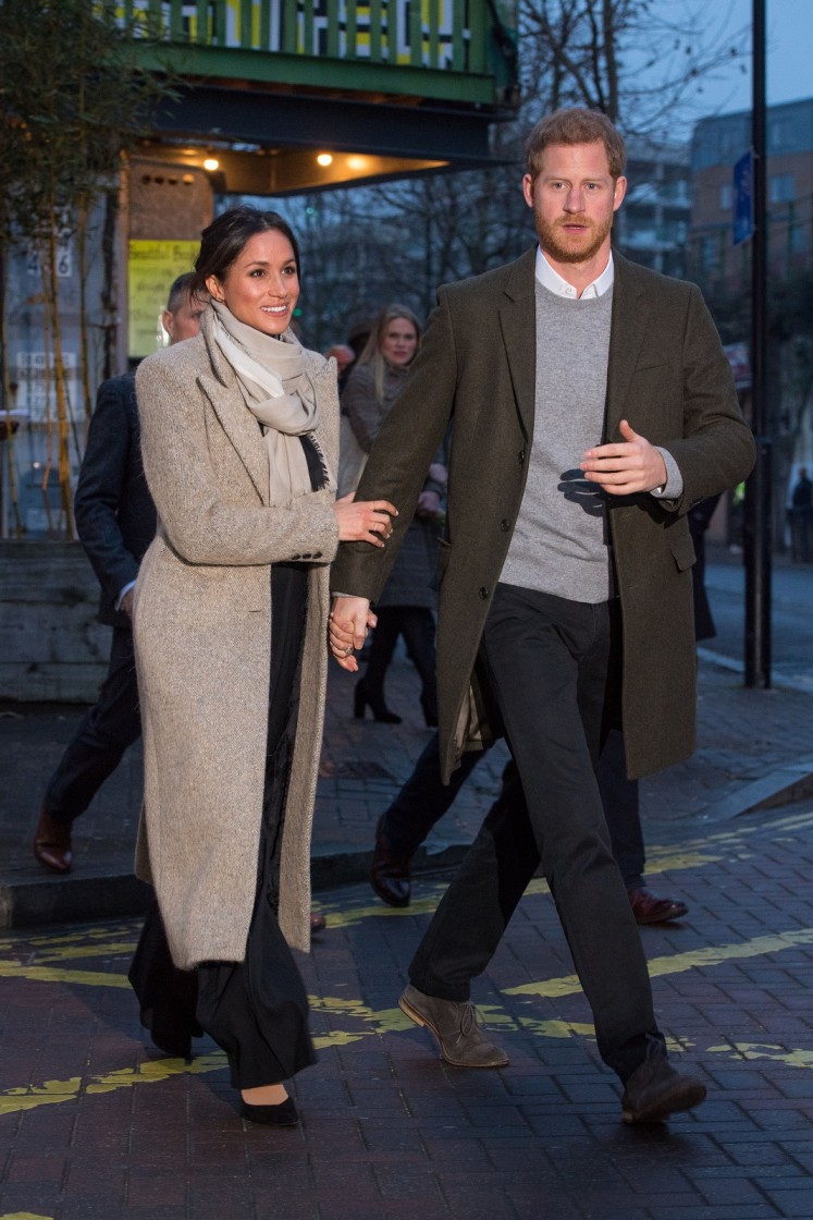 Britain's Prince Harry (R) and his fiancée, US actress Meghan Markle walk out to meet well-wishers as they leave after a visit to Reprezent 107.3FM community radio station in Brixton, south west London on January 9, 2018. 