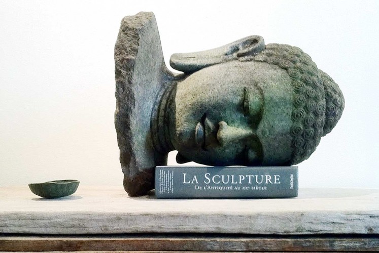 The imitation of the Buddha head as a book holder that Indonesian-born artist Ari Bayuaji created is a symbol of how meaningless the original pieces are if not placed in their rightful place.