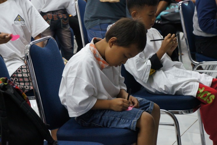 A child that was invited to Streetizens' New Year's Celebration event at Wisma ADR in Penjaringan, North Jakarta, on Jan. 13 writes his wish for the new year on a piece of heart-shaped paper.
