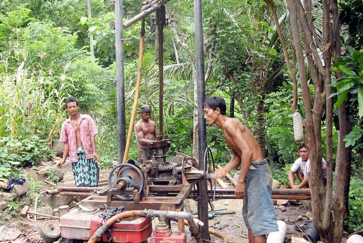 Raising water: Residents operate a water well drilling rig to access safe drinking water.