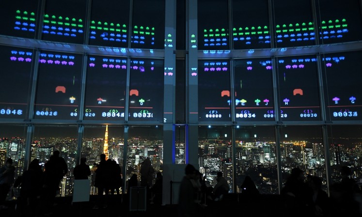 The aliens dropped down the window panes of a Tokyo skyscraper before being blasted into oblivion by enthusiastic gamers celebrating fourty years of the arcade sensation 'Space Invaders'.