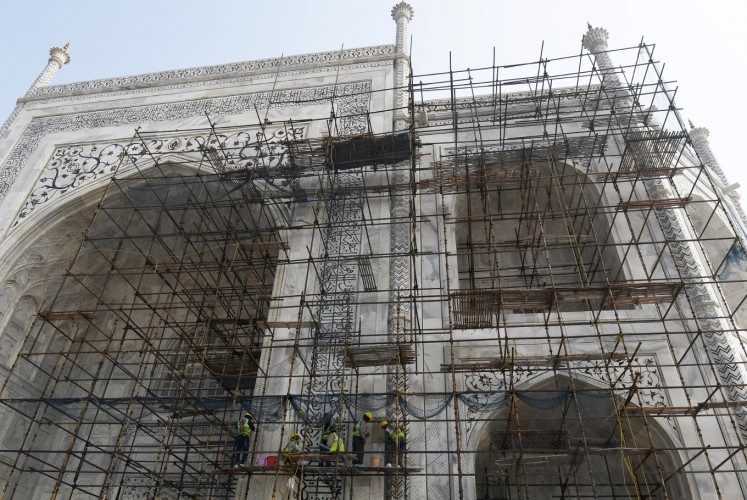 In this photograph taken on January 3, 2018, Indian labourers work amid scaffolding during conservation work at the Taj Mahal in Agra. Restoration work at India's most popular tourist attraction has been dragging on for years, blighting views for tourists, but authorities have not even begun work on the unmissable centrepiece of the 17th-century icon -- its imposing dome.