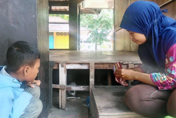 Here, kitty: Dwi Lina (right) and her son, Reno, feed a stray cat.