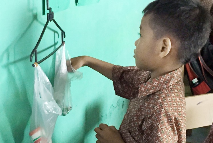 Balancing act: A first grader at SDN 1 Lopok learns how to measure weight using a coat hanger suspended on the wall. Teachers at the school are learning how to use their innate creativity to engage students in active learning through the INOVASI education program.