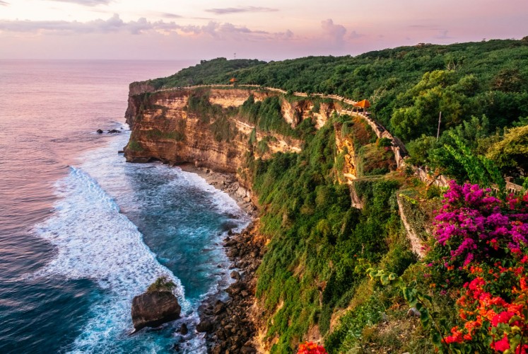 Sunset casts a rosy hue over the cliffs of Uluwatu in southwestern Bali.