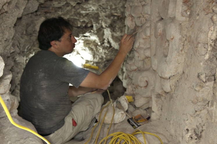 Undated handout picture released by El Zotz Archaeological Project showing archaeologist Edwin Roman working on a bas-relief depicting the Night Sun found under a pyramid at the Zotz archaeological site, in the Peten jungle, 550 km north of Guatemala City. 