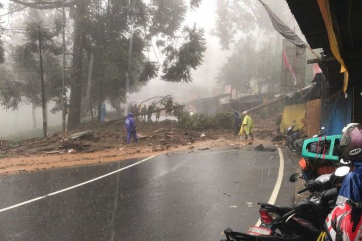 Some officers work on fallen trees blocking the road in Puncak, Bogor, West Java, on Monday.