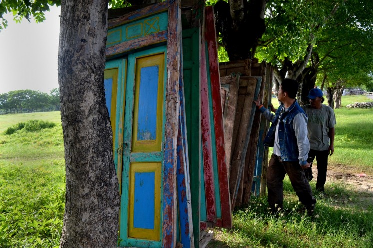 An antique dealer shows old doors of Madurese houses to a potential buyer.