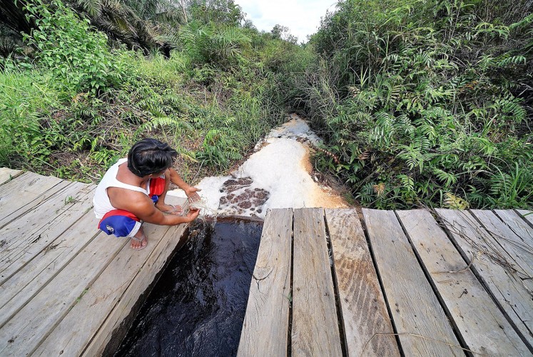 Controlling water: A man inspects a canal partition in Pandan Sejahtera village, which is used to regulate the release of water onto the peatland.