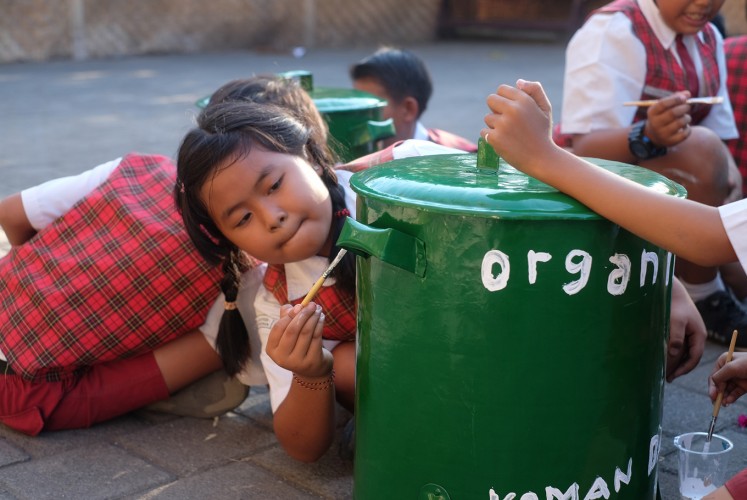 Students from local school paint on a trashcan.