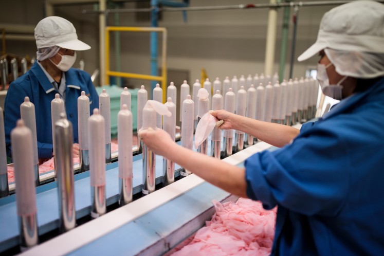In this picture taken on January 25, 2018, employees of Japanese condom maker Sagami Rubber Industries perform quality tests for randomly picked condoms at the company's testing facility in Atsugi, Kanagawa prefecture.