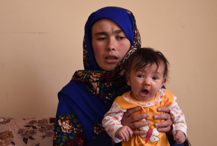 This picture taken on March 24, 2018 shows Afghan mother Jahantab Ahmadi, 25, holding her youngest child during an interview with AFP at a house in Kabul. 