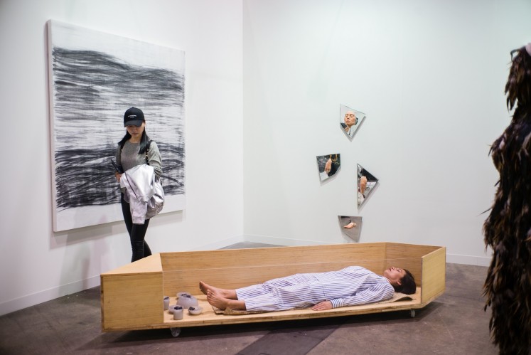 A visitor walks past Danish artist Lilibeth Cuenca Rasmussen's performance piece 'Re-inventing Domesticity and the Decomposing of the Self' during the media preview of Art Basel in Hong Kong on March 27, 2018.