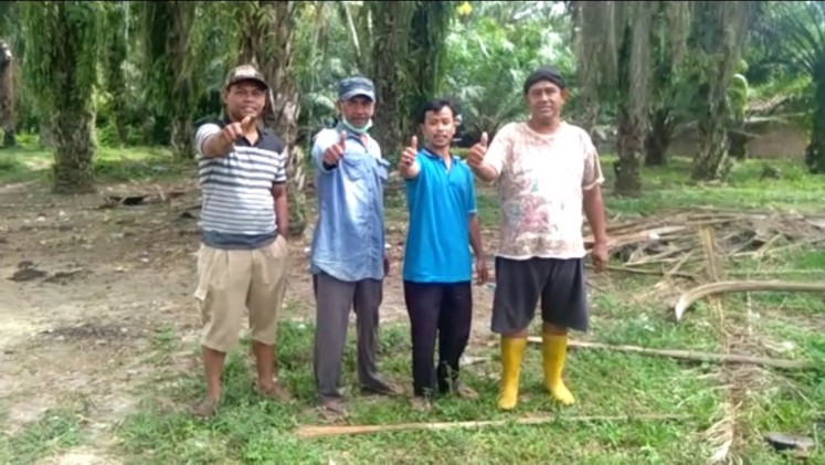 Tugimin (right) poses with his friends at his palm oil plantation in Simalungun regency, North Sumatra.