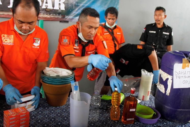Sampling: Crime scene investigators from the Bandung Police check bottles found on Thursday in a house suspected to be a production site of bootleg liquor in Bandung regency of West Java.