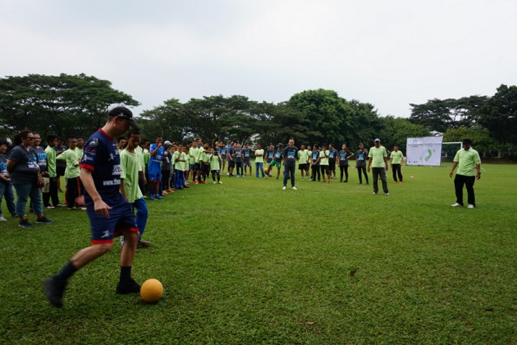 Lee Hawkins (left), technical manager of ASA Foundation, kicks a ball to commence StarCoach, a project between Starbucks and ASA Foundation, on April 15, at Global Jaya School in South Tangerang, Banten. 