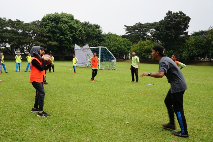 A student learns to pass a ball with a Starbucks employee for  the StarCoach project at Global Jaya School in South Tangerang, Banten, on, April 15.