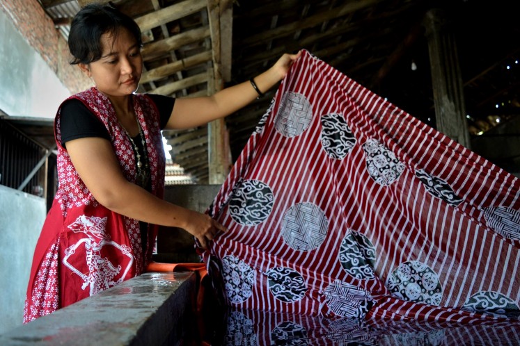 Anik Ermawati observes her stamped batik in her workshop in Premulung village, Laweyan, Surakarta.