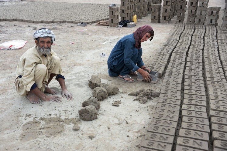 This photograph taken on March 11, 2018 shows Afghan female labourer Sitara Wafadar, 18, who dresses as a male in order to support her family, working at a brick factory next to her elderly father (L) in Sultanpur village in Surkh Rod district, in Afghanistan's eastern Nangarhar province.