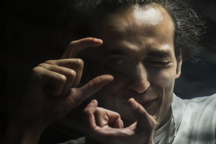 In this file photo taken on August 9, 2016 shows Egyptian photographer Mahmoud Abu Zeid, known as Shawkan, gesturing from inside a soundproof glass dock, during his trial in the capital Cairo on August 9, 2016.