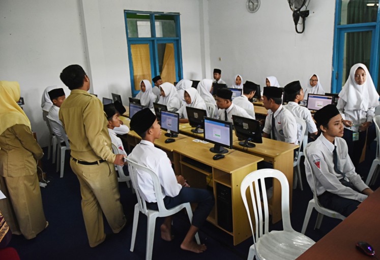 Get ready: Teachers give instructions to students of  Madrasah Tsanawiyah Hidayatul Mubtadiin junior high school in Malang, East Java, before they start the computer-based national exams on April 23.