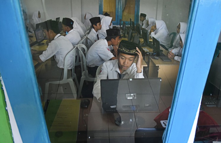 Hard task: Students at Islamic junior high school Madrasah Tsanawiyah Hidayatul Mubtadi'in in Malang, East Java take an Indonesian language test on the first day of the computer-based national exams on April 23. 