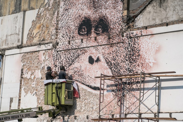 Portuguese street artist Vhils chisels an orangutan’s face on the side of a building at the Majestik traffic circle area in Medan in March.