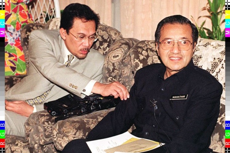 Anwar Ibrahim removes a ball of dust from  Mahathir's sleeve during a press conference in 1997.