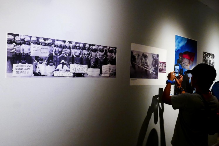 Visitors look at photos from Indonesia's reformation period. 
