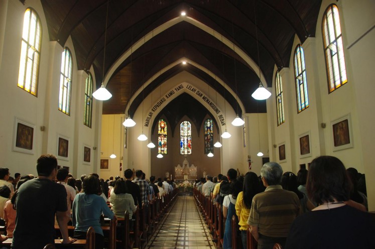 Congregants attend a Sunday service, as police stand guard outside, in Saint Peter's Church in Bandung, West Java, on Sunday. A wave of blasts including a suicide bombing struck churches in Surabaya, East Java, on Sunday, killing at least 10 and wounding dozens of others, police have said.