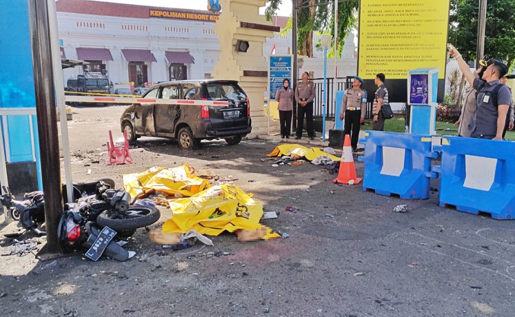 On alert: Security officers watch the wreckage of a motorcycle used by suicide bombing perpetrators during their attack in front of the Surabaya Police headquarters in East Java on May 14. 