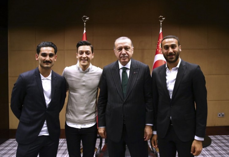 This handout picture taken and released on May 13, 2018 and released on May 14, 2018 by the Turkish Presidential Press office shows Turkish President Recep Tayyip Erdogan(second right) posing for a photo with Turkish football players Ilkay Gundogan (left), Mesut Ozil (2nd left) and Cenk Tosun (right) in London. 
