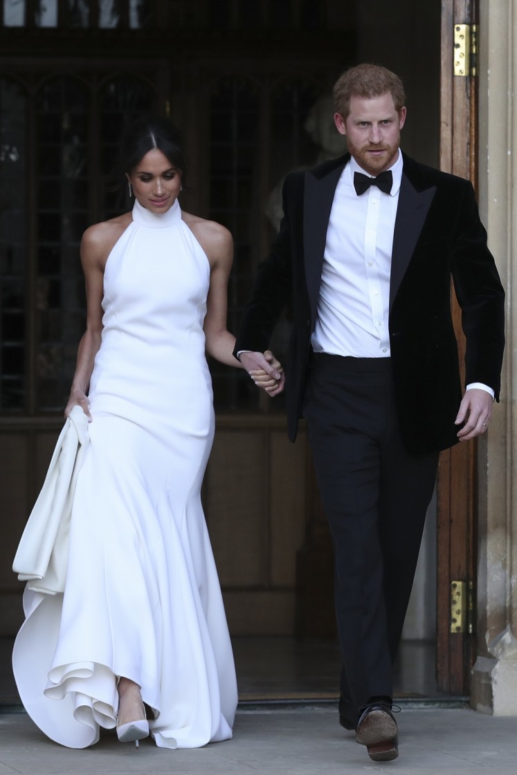 The newly married Britain's Prince Harry, Duke of Sussex, (R) and Meghan Markle, Duchess of Sussex, (L) leave Windsor Castle in Windsor on May 19, 2018 after their wedding to attend an evening reception at Frogmore House. 