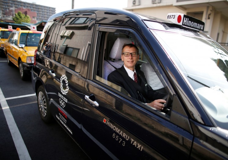 Wolfgang Loeger from Austria, a taxi driver of Hinomaru Kotsu Co., poses for a photograph inside a 'JPN Taxi' car, developed by Toyota Motor Co., in Tokyo, Japan May 14, 2018.
