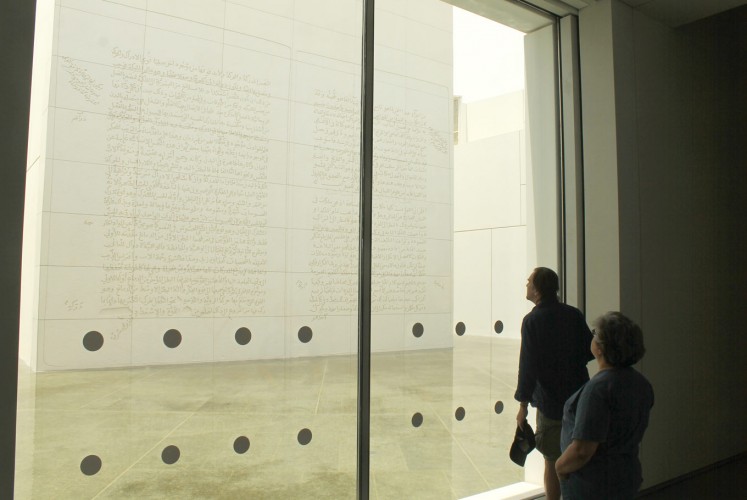 Watch and wonder: Visitors admire American visual artist Jenny Holzer’s limestone relief emblazoned with three pages of Arabic script, made in 2007. In the amphibious museum, the relief’s foundation stands on seawater.