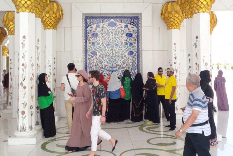 Just passing by: Visitors walk through the Sheikh Zayed Grand Mosque’s hallway area, which is decoration and designed to evoke a Persian influence. At the center, thirsty guests line up to drink from a fountain water.